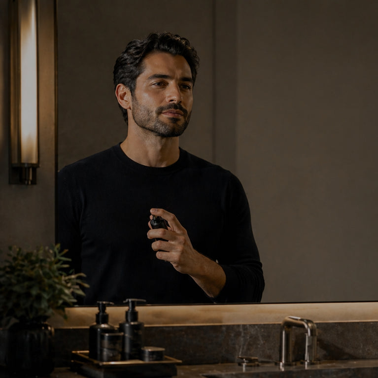 Man applying makeup in front of a mirror in a bathroom.